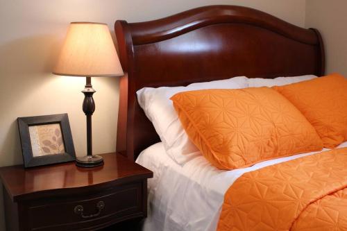 a bed with an orange pillow and a lamp on a nightstand at 2-Bedroom basement suite with a separate entrance. in Abbotsford