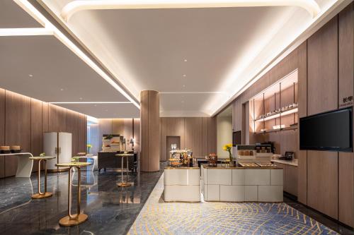 a large kitchen with wooden cabinets and tables in a room at HUALUXE Shanghai Changfeng Park - Park Lake View in Shanghai
