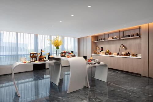a lobby with two white tables and a kitchen at HUALUXE Shanghai Changfeng Park - Park Lake View in Shanghai