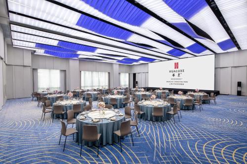 a banquet hall with tables and chairs and a screen at HUALUXE Shanghai Changfeng Park - Park Lake View in Shanghai
