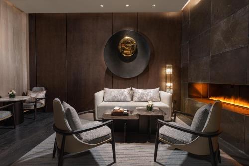 a living room with a couch and chairs and a fireplace at HUALUXE Shanghai Changfeng Park - Park Lake View in Shanghai