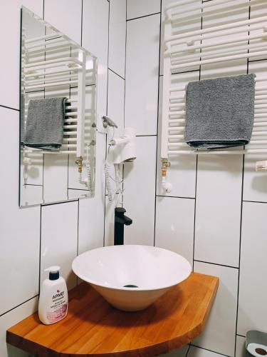 a bathroom with a white bowl sink on a wooden table at Pokoje Jola in Drawsko Pomorskie