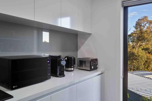 a kitchen with two microwaves on a counter next to a window at Izzys Retreat in Creswick