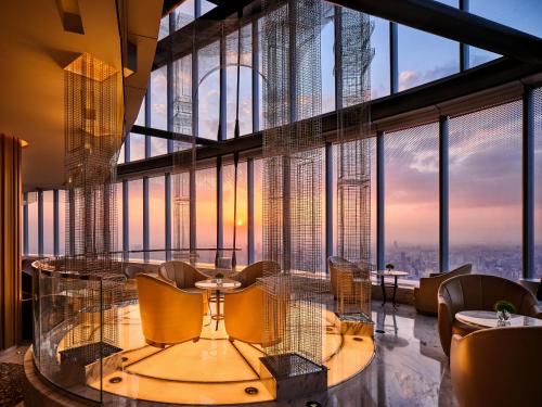 a restaurant with a glass table and chairs in front of a large window at J Hotel, Shanghai Tower - Above All Else, Overlooking the Bund in Shanghai