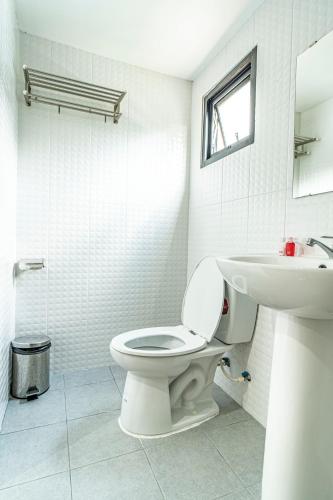 a white bathroom with a toilet and a sink at Laewan Guesthouse in Baan Tai