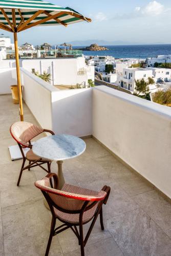 a table and chairs on a balcony with a view of the ocean at Pelican Bay Hotel in Platis Yialos Mykonos