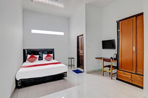 1 dormitorio con cama y escritorio. en OYO 92057 Reny Kost Syariah en Jambi