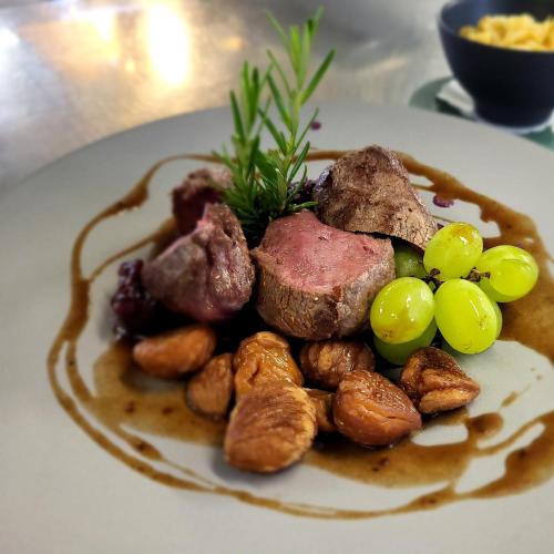 a plate of food with meat and grapes on a table at Hotel-Restaurant Eyholz in Visp