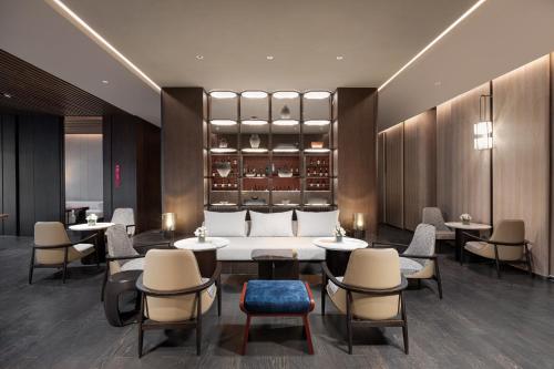 a hotel lobby with tables and chairs and a couch at HUALUXE Shanghai Changfeng Park - Park Lake View in Shanghai