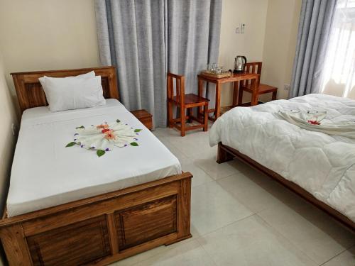 a bedroom with two beds and a table and chairs at Kendwa Cool and Calm Hotel limited in Kendwa