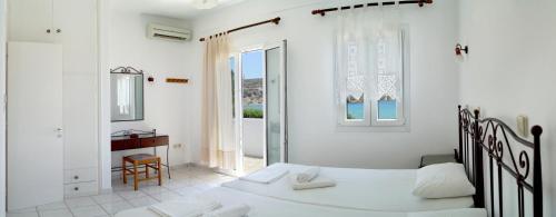 1 dormitorio con 2 camas blancas y ventana en LEANDROS APARTMENTS en Platís Yialós Sifnos
