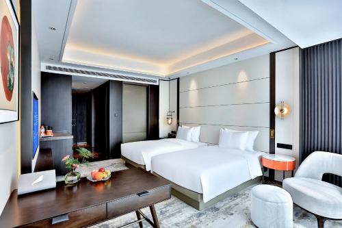 um quarto de hotel com duas camas e uma secretária em 银都酒店 Yandoo Hotel em Yiwu