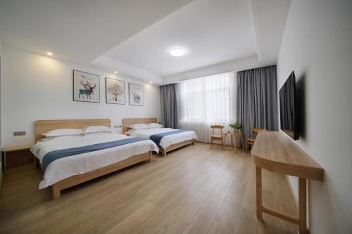 ein Hotelzimmer mit 2 Betten und einem Tisch in der Unterkunft Qianxun Tea House & Homestay in Wuyishan