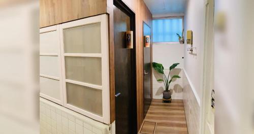 a hallway with a door to a bathroom with a plant at ペンションやいま日和 in Ishigaki Island
