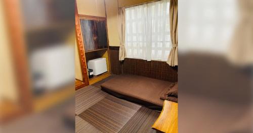 a small room with a bed and a window at ペンションやいま日和 in Ishigaki Island