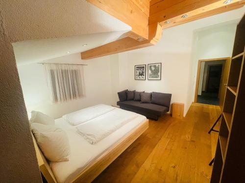 Natursport Heutal Appartements في أونكن: غرفة نوم صغيرة مع سرير وأريكة