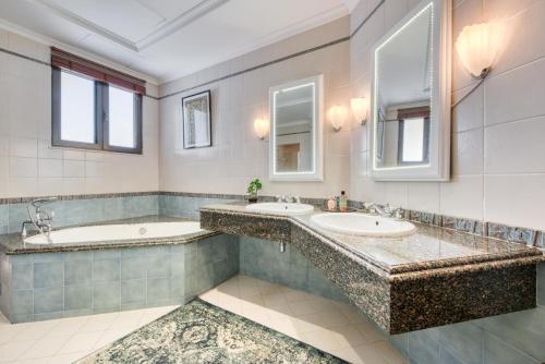 a bathroom with two sinks and two mirrors at Maison Privee - Glamourous Beachfront Villa on The Palm with Pool in Dubai