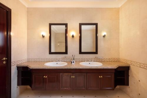 a bathroom with two sinks and two mirrors at Maison Privee - 5 Stars Villa with Private Pool or Beach on Palm Jumeirah in Dubai