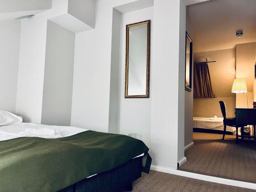 Schlafzimmer mit einem Bett, einem Spiegel und einem Tisch in der Unterkunft Arctic Hotel Nordkapp in Honningsvåg