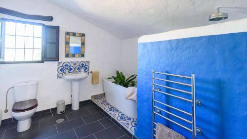 uma casa de banho azul e branca com um WC e um lavatório em Casa Belmonte Alcaucín by Ruralidays em Alcaucín
