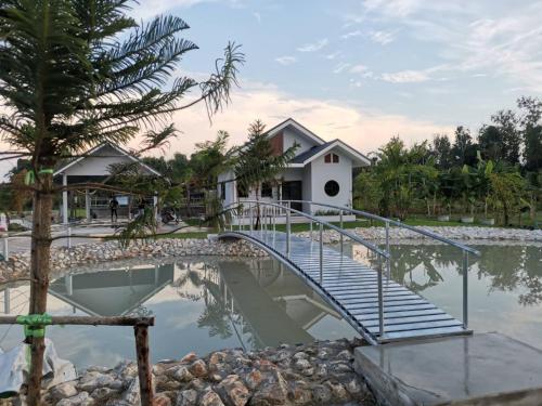 a bridge over a pond in front of a house at Numhom Resort in Ban Nong Chum Saeng