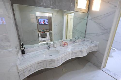a white bathroom with a sink and a mirror at Al Wadi House , بيت الوادي in Ras al Khaimah
