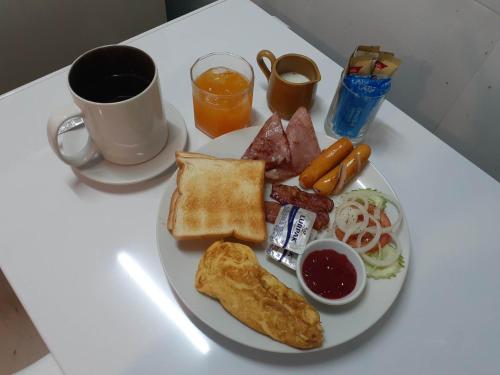 een bord ontbijtproducten op een tafel met een kopje koffie bij Phratamnak Inn guesthouse - 100 mtr from the beach in Pattaya South