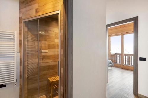 una puerta de ducha de cristal en una habitación con balcón en Plaz en Livigno