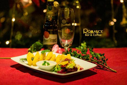 a plate of food on a table with a glass of wine at Romance Hotel in Hue