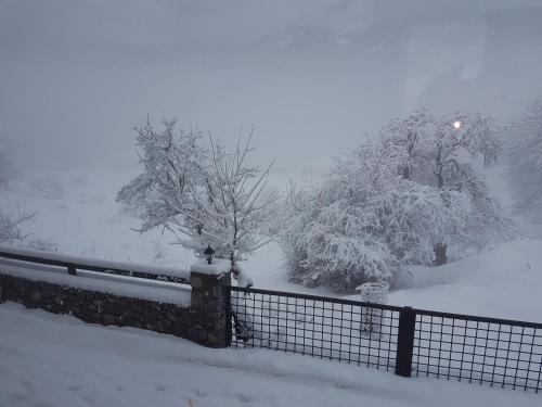 a fence covered in snow with trees in the background at Mountain house in Palaios Agios Athanasios