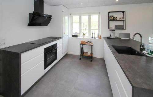 a kitchen with white cabinets and a black counter top at 4 Bedroom Gorgeous Home In Samsø in Ballen