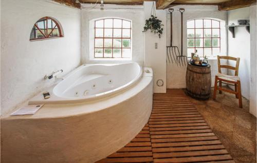 una gran bañera blanca en una habitación con ventanas en Awesome Home In Sams With Kitchen, en Onsbjerg