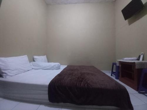 - une chambre avec un lit avec des draps blancs et une table dans l'établissement EKSOTIS ROOMS SYARIAH, à Seturan