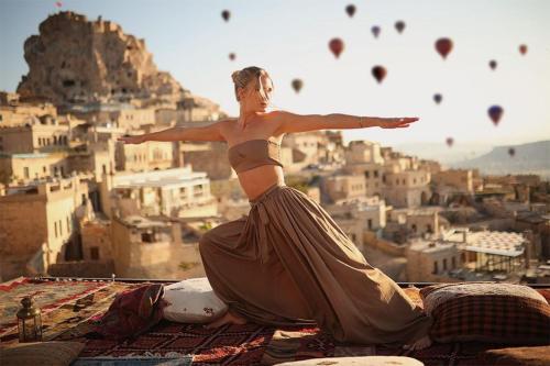 a woman in a dress sitting on top of a city at Mak's Cave House in Uchisar