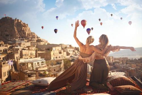 two women standing on top of a building with hot air balloons at Mak's Cave House in Uchisar