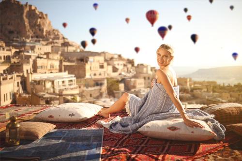 a woman sitting on pillows with hot air balloons at Mak's Cave House in Uchisar
