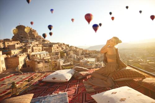 a woman sitting on top of a tower with hot air balloons at Mak's Cave House in Uchisar