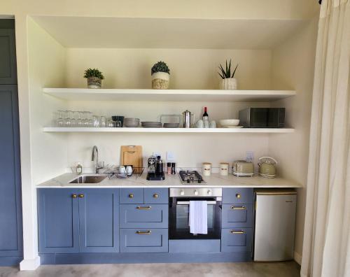 a kitchen with blue cabinets and a sink and shelves at Little Prestwick on Gowrie Farm, Nottingham Road in Nottingham Road