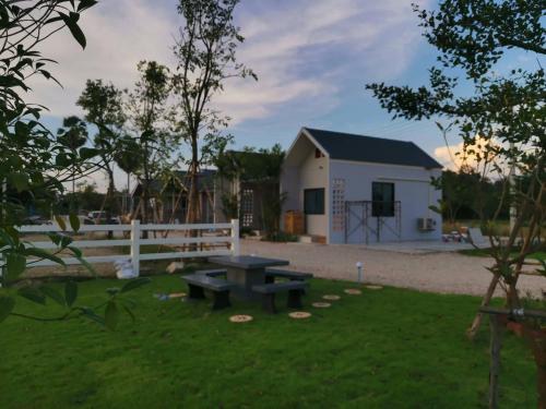 a picnic table in a yard with a fence and a building at Numhom Resort in Ban Nong Chum Saeng