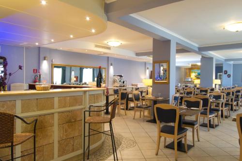 切薩雷奧港的住宿－Conchiglia Azzurra Resort & Beach，一间带桌椅的餐厅和一间酒吧
