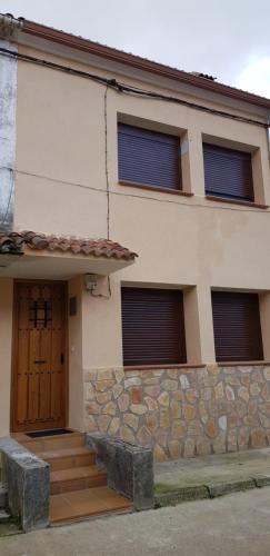 un edificio con una puerta marrón y una pared de piedra en CASA La Playeta, en Puente de Vadillos