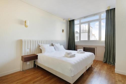 une chambre avec un grand lit blanc et une fenêtre dans l'établissement Pick A Flat's Apartment in Opéra - Rue Saint Marc, à Paris