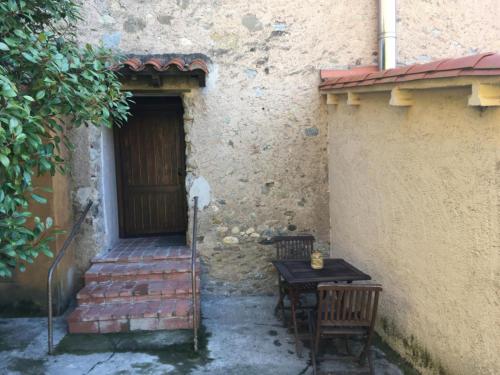 un edificio con 2 sillas y una puerta de madera en Els Arenys, en Sant Joan de les Abadesses