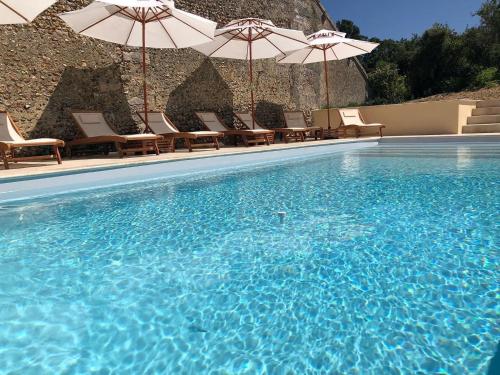 a large swimming pool with chairs and umbrellas at Maison d'hôtes le Prieuré du Preux 