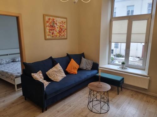 a living room with a blue couch and a window at Igo apartment Uzupis in Vilnius