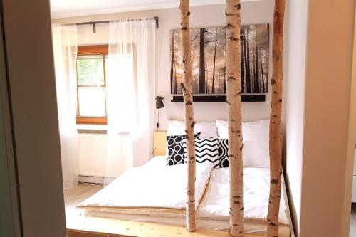 een slaapkamer met een hemelbed met berken bij Zimmer mit kleiner Dachterrasse / App. WALD byTILLY in Velden am Wörthersee