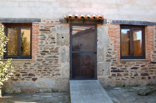 a stone building with a wooden door and windows at Casita del jardin in El Bodón