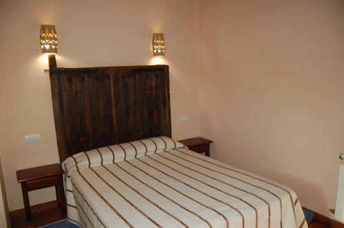 a bedroom with a bed with a striped blanket at Casita del jardin in El Bodón