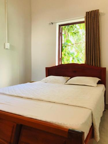 a bedroom with a large bed with a window at SUNNY Homestay Mui Ne in Phan Thiet