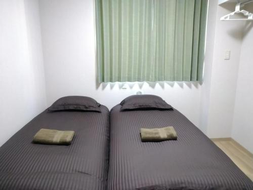 2 camas individuales en un dormitorio con ventana en Hitoyado Ryokan Higashiueno - Vacation STAY 72556v, en Tokio